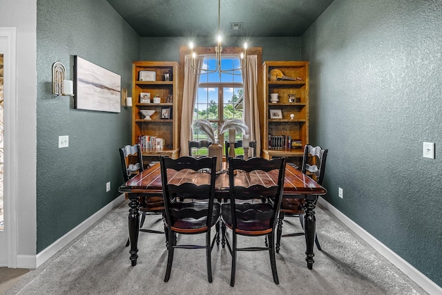 dining area featuring carpet floors, a textured wall, baseboards, and an inviting chandelier