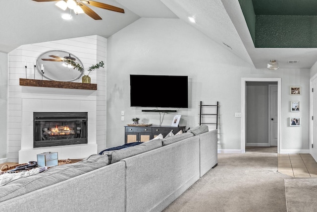 living room with light carpet, baseboards, a ceiling fan, a tile fireplace, and vaulted ceiling