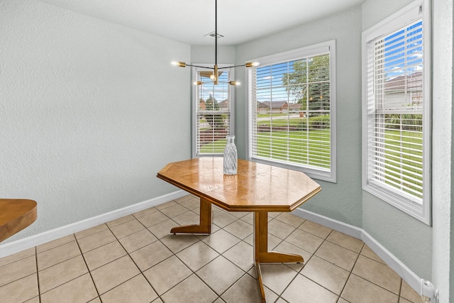 unfurnished dining area with a chandelier, a healthy amount of sunlight, baseboards, and light tile patterned floors