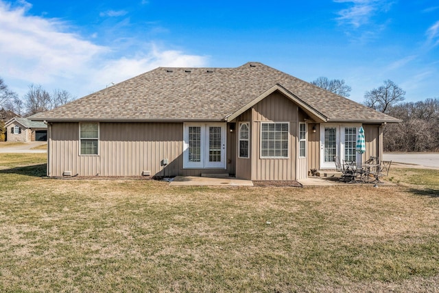 rear view of house with a shingled roof, a lawn, a patio area, and board and batten siding