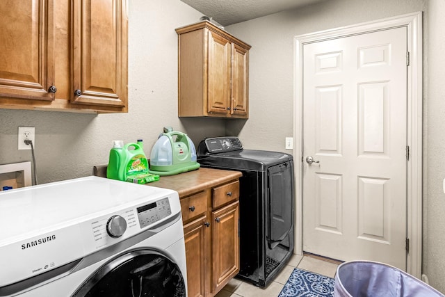 laundry area with washer and dryer, cabinet space, a textured ceiling, and light tile patterned floors