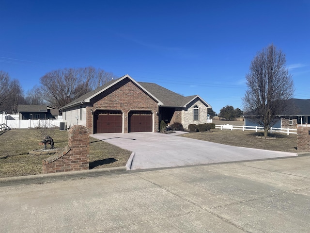 view of front of home with central AC unit, a garage, brick siding, fence, and driveway