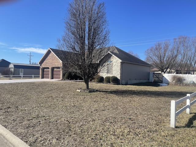 view of front of house with driveway, stone siding, an attached garage, and fence