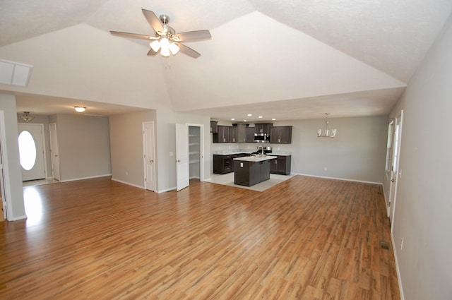 unfurnished living room with high vaulted ceiling, baseboards, wood finished floors, and ceiling fan with notable chandelier