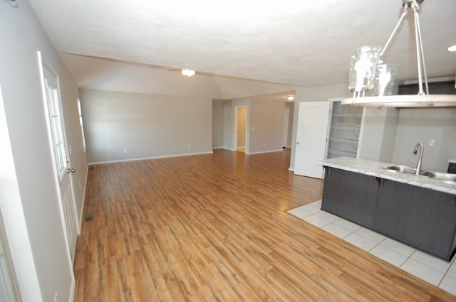 kitchen with open floor plan, light countertops, a sink, and light wood-style flooring