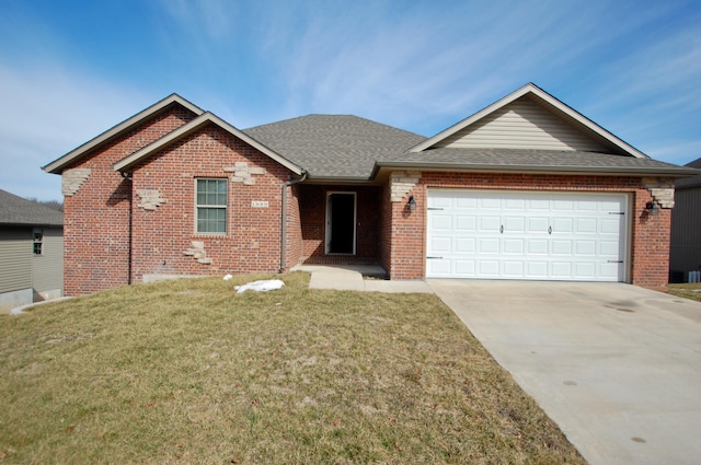 single story home with driveway, a garage, a shingled roof, brick siding, and a front yard