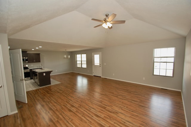 unfurnished living room featuring dark wood-style flooring, lofted ceiling, recessed lighting, baseboards, and ceiling fan with notable chandelier