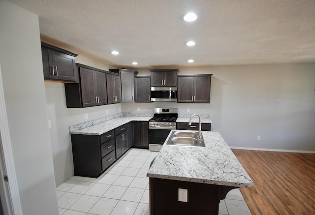 kitchen with dark brown cabinetry, recessed lighting, a sink, appliances with stainless steel finishes, and a center island with sink