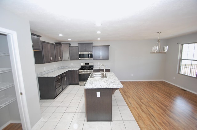 kitchen featuring stainless steel appliances, a kitchen island with sink, a sink, and dark brown cabinetry