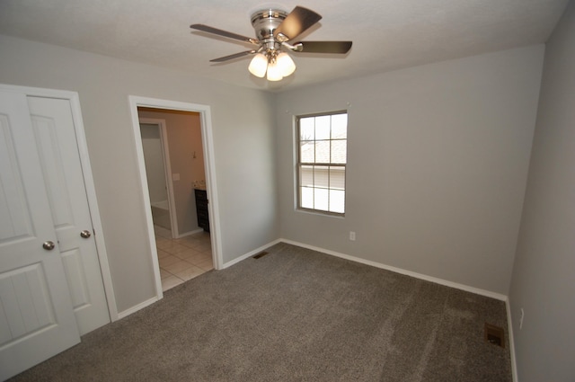 unfurnished bedroom with ensuite bath, carpet, visible vents, and baseboards