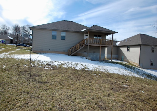 snow covered back of property featuring stairway and a yard