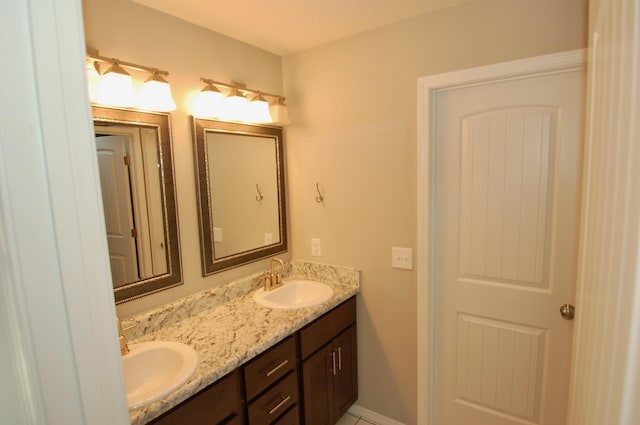 bathroom featuring double vanity, baseboards, and a sink