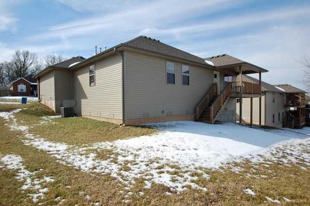 snow covered back of property with stairs and cooling unit