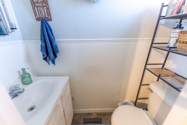 bathroom featuring wainscoting, visible vents, vanity, and toilet