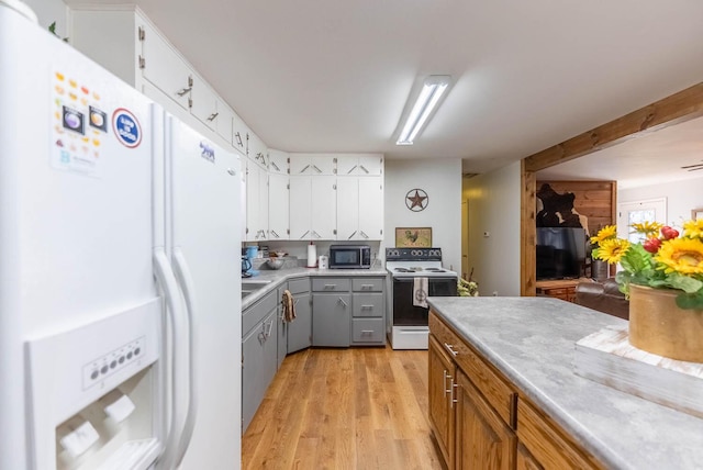 kitchen featuring white appliances, light countertops, light wood finished floors, and white cabinetry