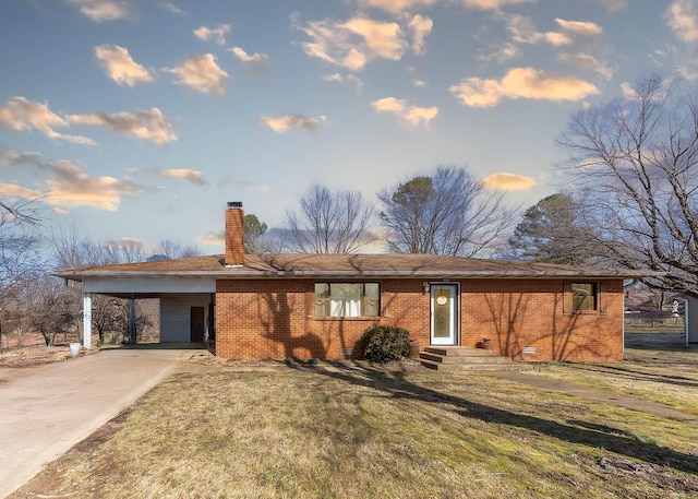 view of front facade with concrete driveway, a chimney, an attached carport, a front lawn, and brick siding