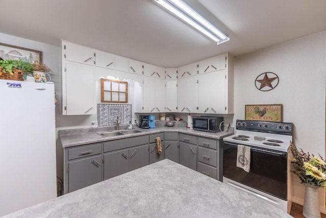 kitchen with light countertops, gray cabinetry, white cabinetry, a sink, and white appliances