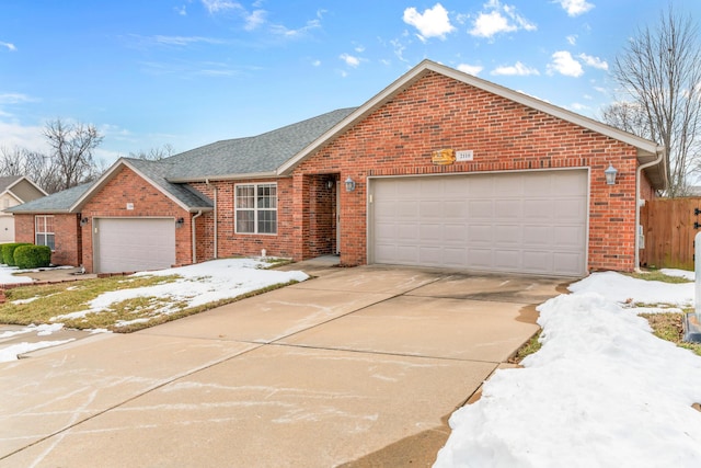 ranch-style home with concrete driveway, brick siding, an attached garage, and roof with shingles