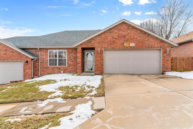 ranch-style house with driveway, roof with shingles, an attached garage, and brick siding