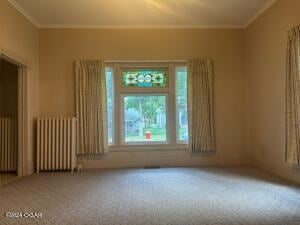 carpeted empty room with radiator heating unit and crown molding