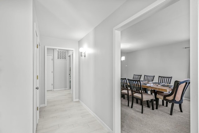 hallway featuring light wood finished floors, visible vents, and baseboards