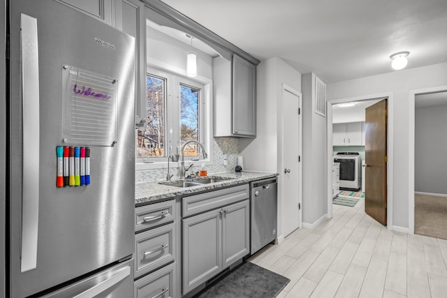 kitchen with washer / clothes dryer, backsplash, stainless steel dishwasher, a sink, and fridge