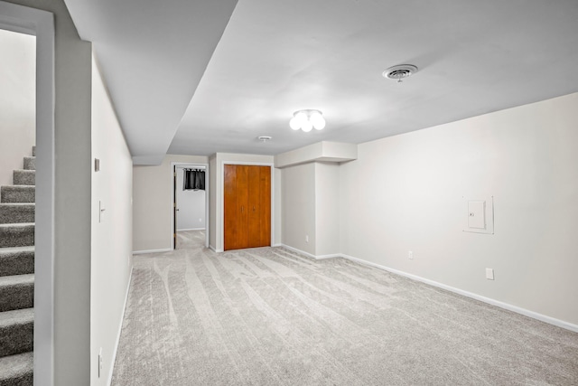 finished basement featuring stairs, light carpet, visible vents, and baseboards