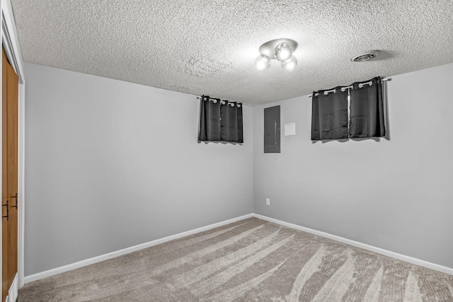 carpeted empty room featuring a textured ceiling, electric panel, and baseboards