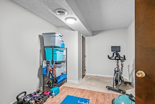 workout room with baseboards, visible vents, and a textured ceiling