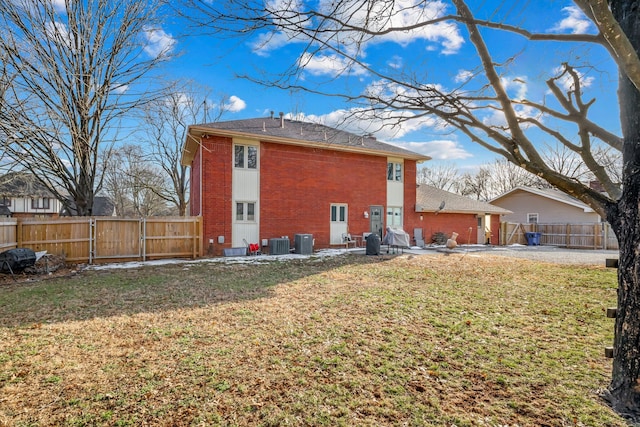 back of property featuring central air condition unit, brick siding, fence, and a lawn