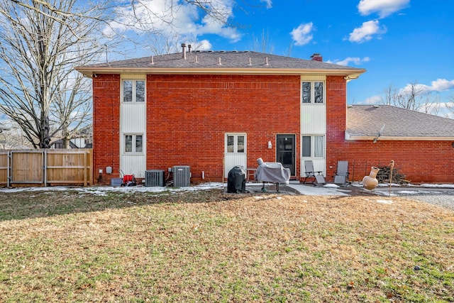 back of house with brick siding, a patio, a chimney, a lawn, and fence