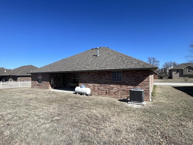 view of home's exterior with central AC unit, roof with shingles, a patio area, and brick siding