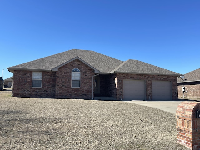 ranch-style house with a shingled roof, brick siding, driveway, and a garage