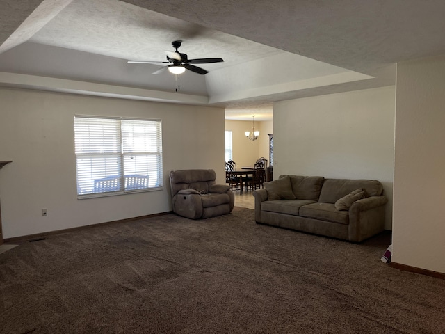 living room featuring dark carpet, a raised ceiling, and baseboards