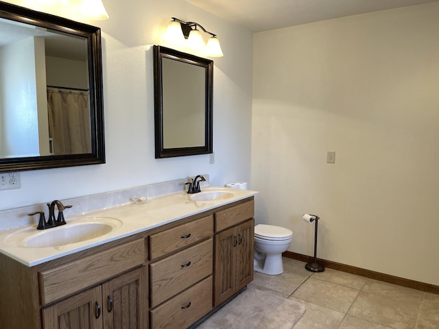 bathroom featuring double vanity, baseboards, toilet, and a sink