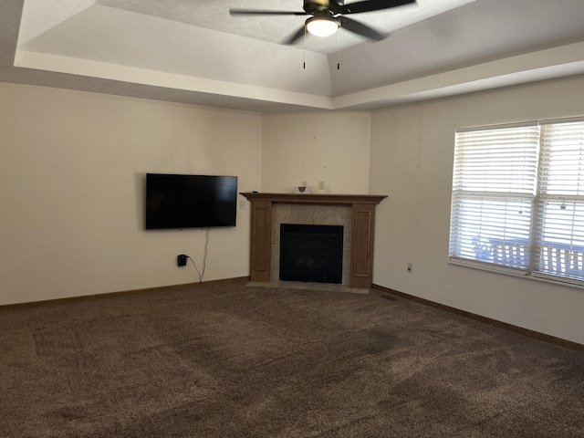 unfurnished living room with a wealth of natural light, carpet, a raised ceiling, and a tile fireplace