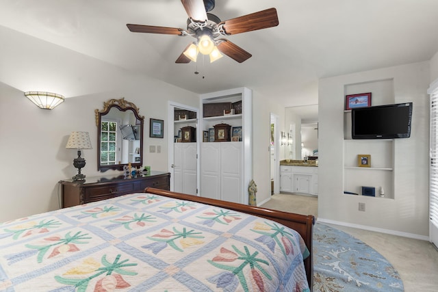 bedroom with light carpet, ceiling fan, baseboards, and connected bathroom