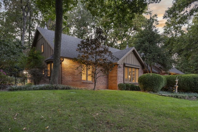 view of front of house featuring a yard, board and batten siding, and brick siding