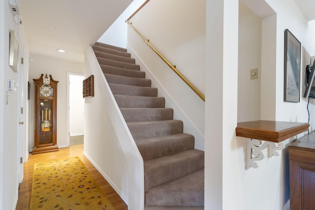 staircase with baseboards, wood finished floors, and recessed lighting