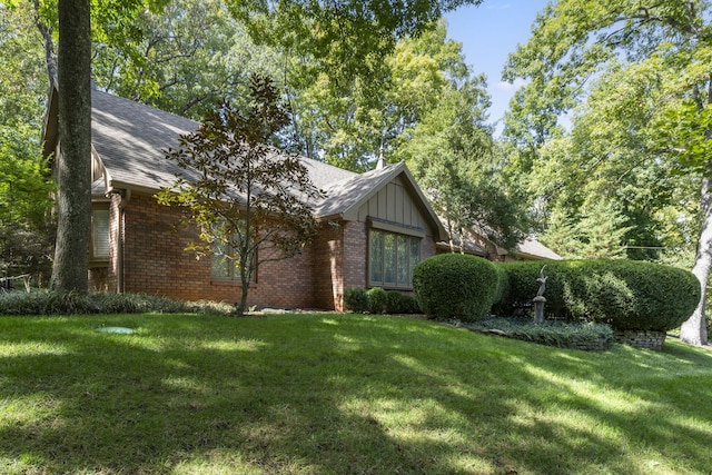 view of front of property featuring roof with shingles, a front lawn, and brick siding