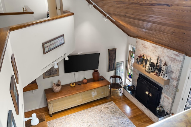 living area with wood ceiling, a large fireplace, baseboards, and wood finished floors