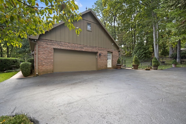 view of home's exterior featuring brick siding, driveway, and fence