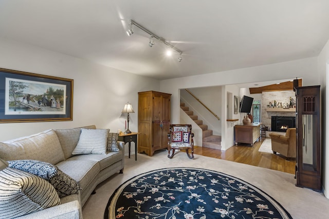 living room featuring light carpet, a lit fireplace, light wood finished floors, and stairway