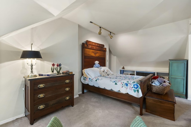 bedroom with lofted ceiling, baseboards, rail lighting, and light colored carpet