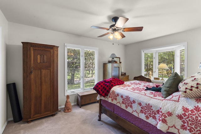 bedroom with a ceiling fan, light colored carpet, and baseboards