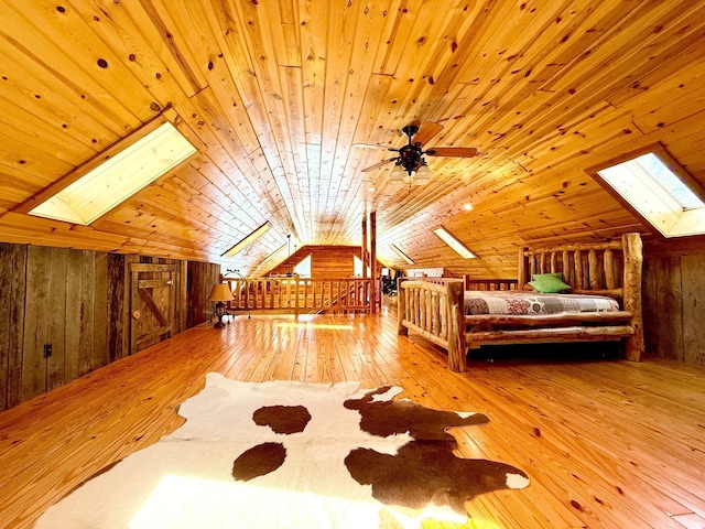 bedroom with wooden ceiling, wood walls, wood-type flooring, and lofted ceiling with skylight