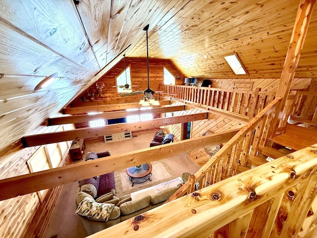 interior space featuring a ceiling fan, lofted ceiling, wood ceiling, and wood walls