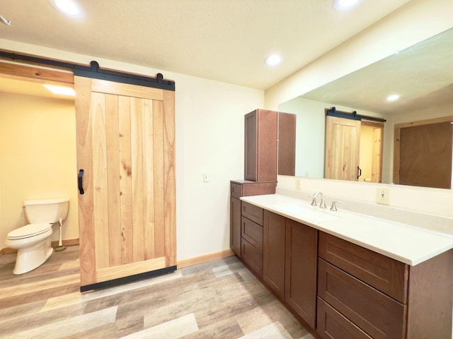 bathroom featuring toilet, wood finished floors, vanity, and recessed lighting