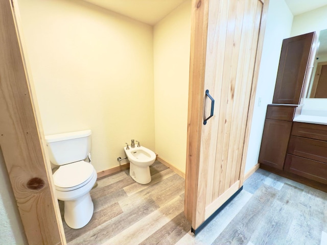 bathroom featuring baseboards, a bidet, toilet, and wood finished floors