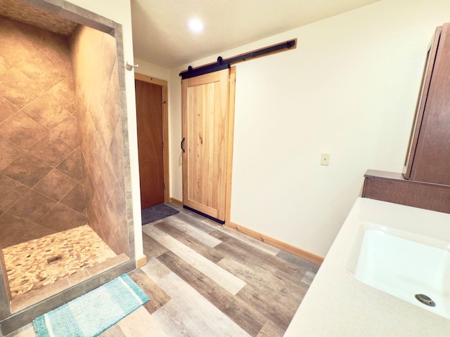 full bath with a stall shower, baseboards, a sink, and wood finished floors